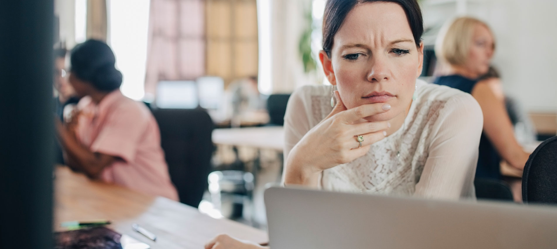 Confused Businesswoman Looking At Laptop While Sitting At Desk