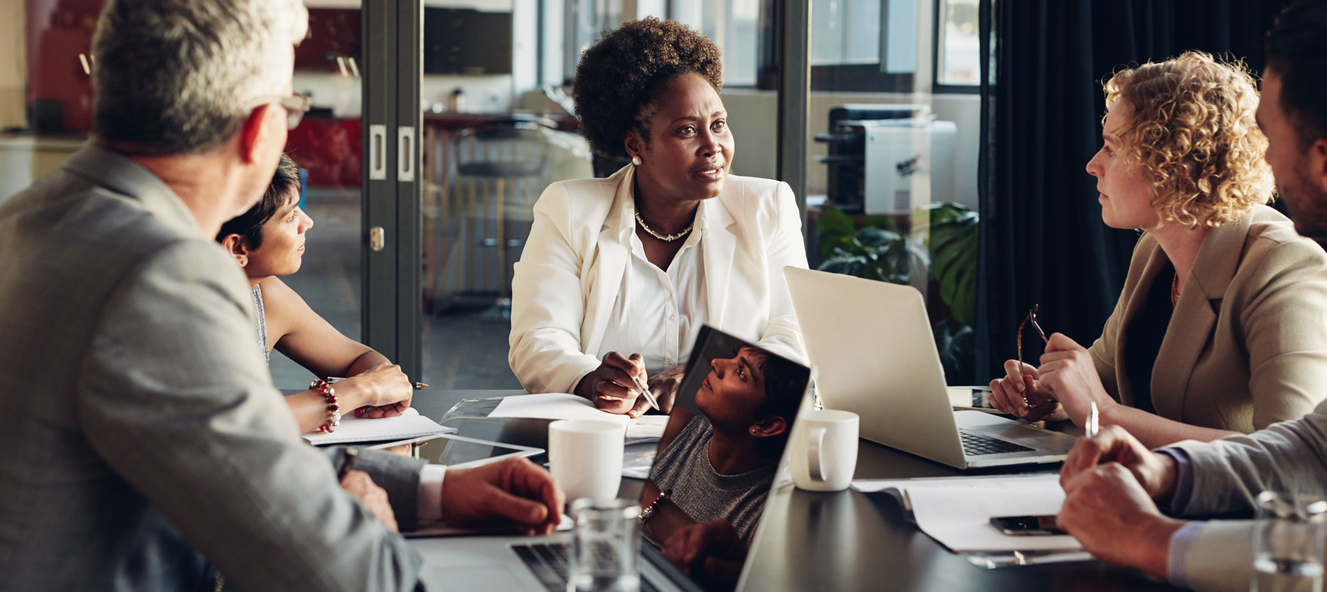 Businesspeople Discussing Work Together Around A Boardroom Table