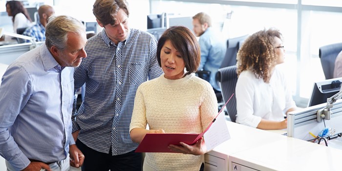 Staff Standing In A Busy Open Plan Office