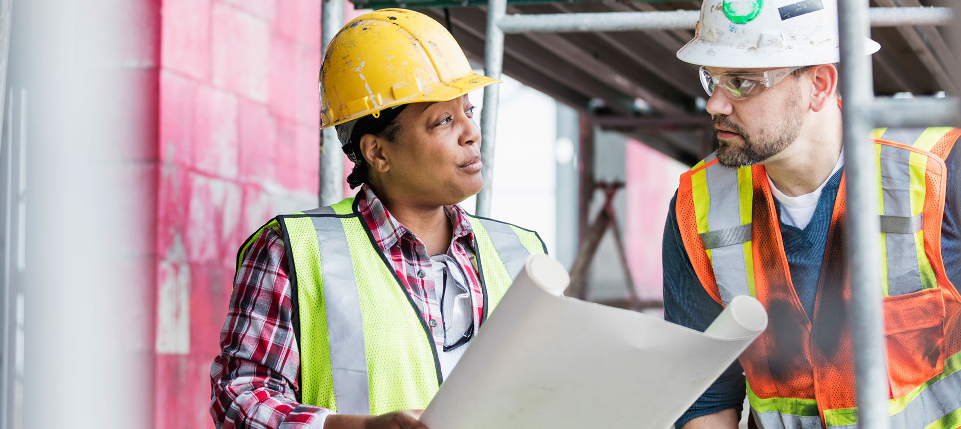 Workers At Construction Site Looking At Plans