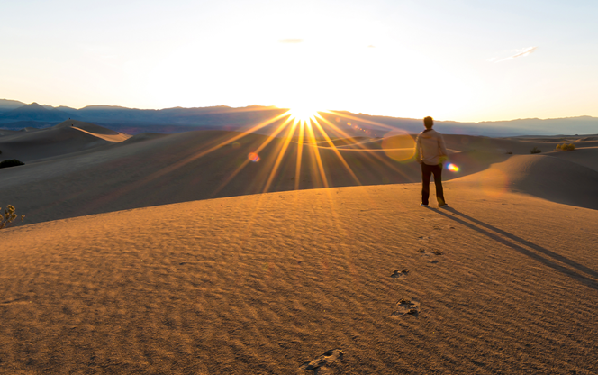 Man Standing And Looking At The Sunrise In The Desert