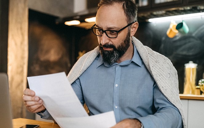 Man Looking At A Document Finding Solution To Pay All Bills