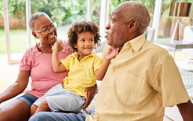 Little Boy Sitting With His Grandparents At Home