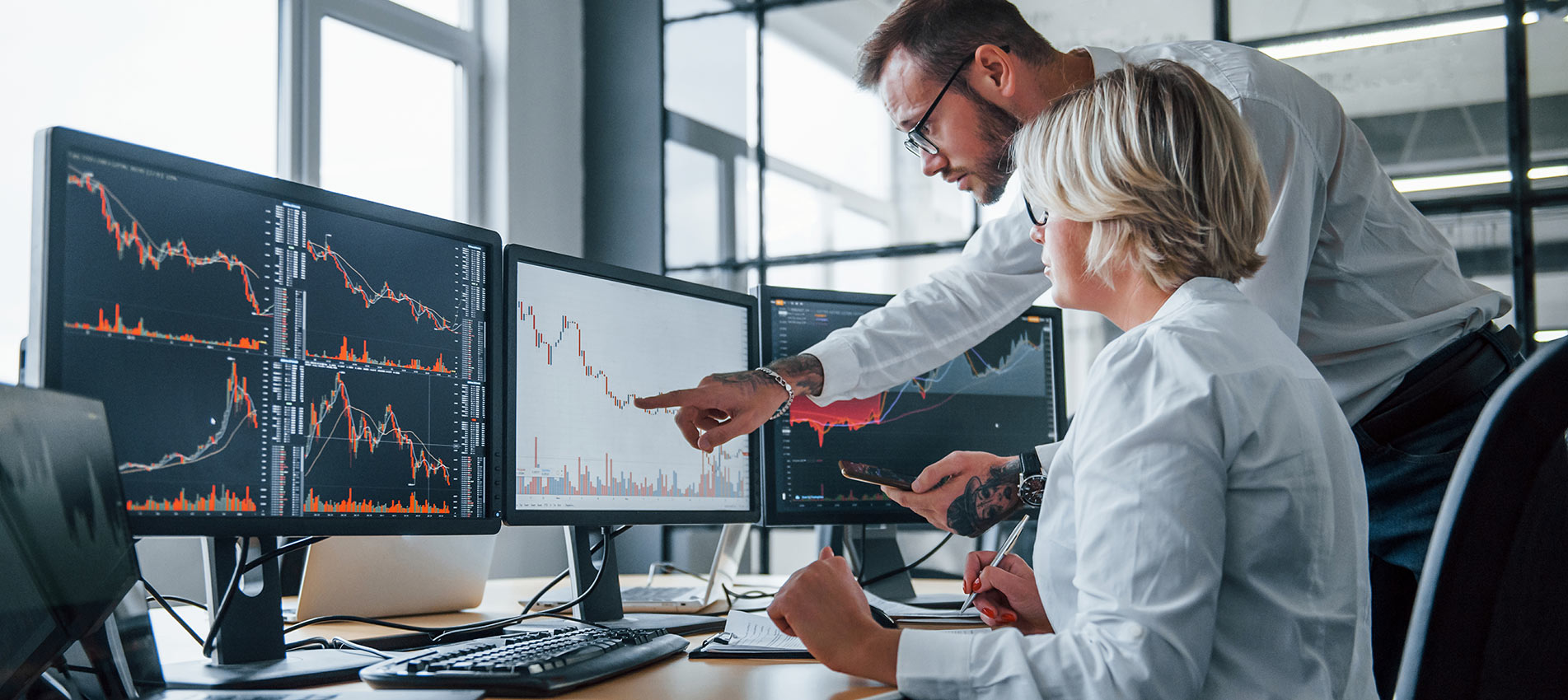 Two Stockbrokers Analyzing Information Together In The Office