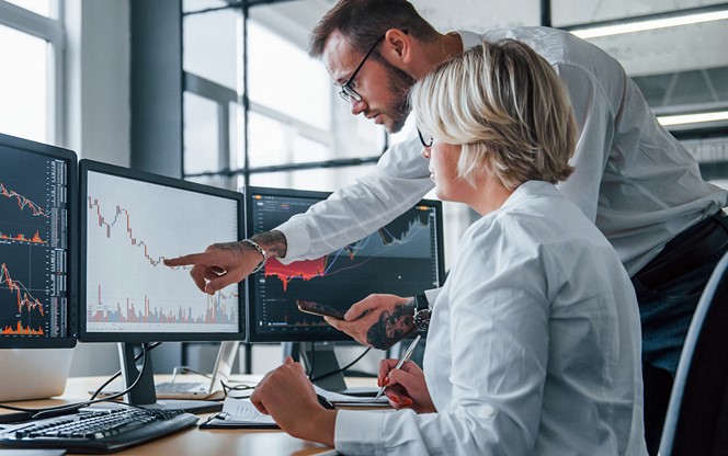 Two Stockbrokers Analyzing Information Together In The Office