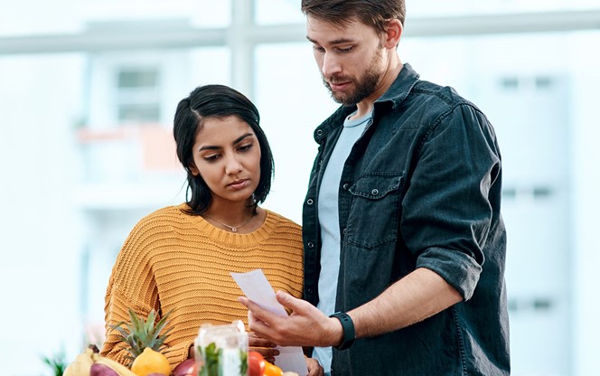 Young Couple Going Through Their Receipts At Home After Buying Groceries