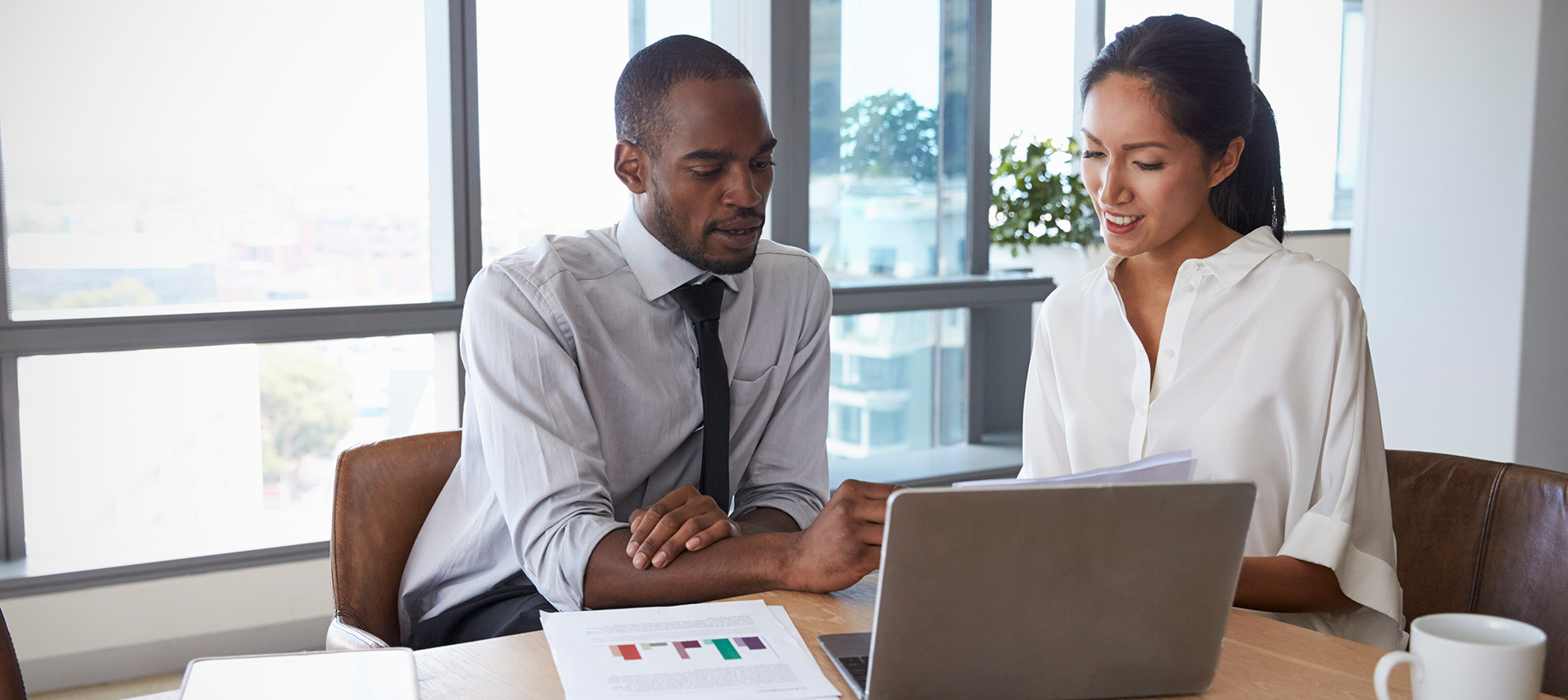 Businesspeople Working On Laptop In Boardroom Together