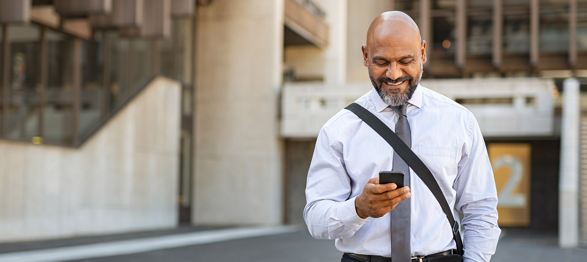 African American Satisfied Businessman Walking While Using Phone