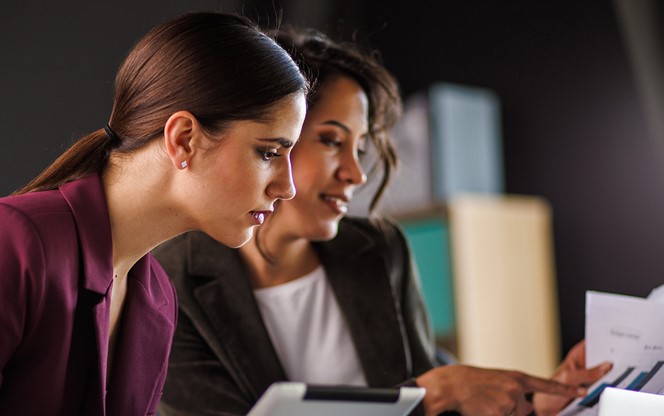 Two Businesswomen Having A Project Meeting Reviewing Data And Discussing Strategie