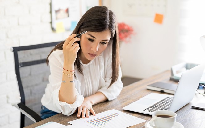 Businesswoman Sitting At Her Table And Looking At Statistical Charts