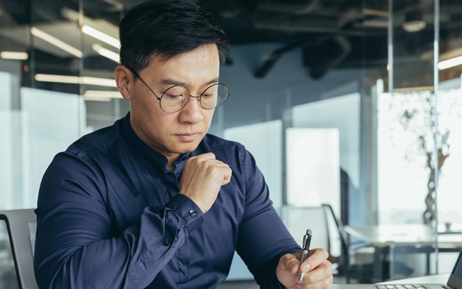 Asian Male Financial Accountant In Glasses Working With Documents And Accounts On Laptop