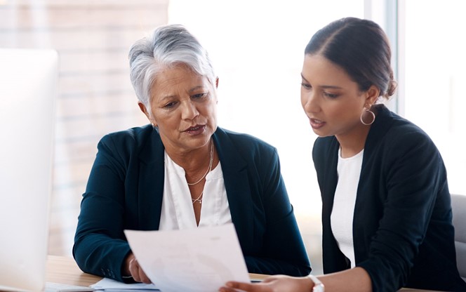 Two Businesswomen Reviewing Retirement Savings Programs Paperwork