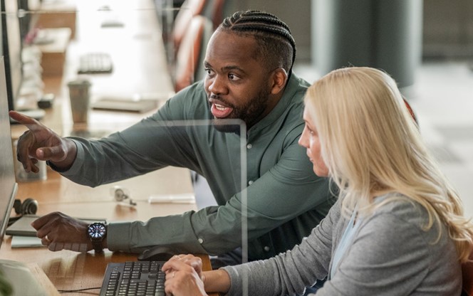 Mid Adult Black Businessman Analyzing Data On Screen With Female Colleague