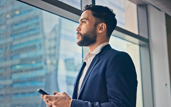 Hispanic Businessman Standing Looking Outside Window