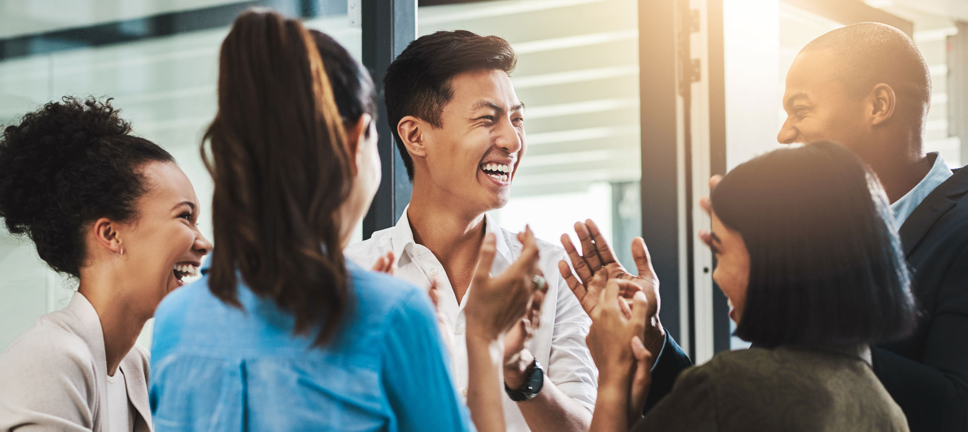 Group Of Young Businesspeople Standing Together And Clapping In A Modern Office