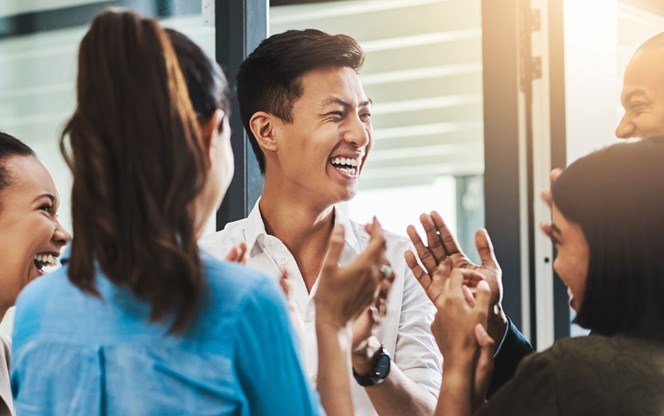 Group Of Young Businesspeople Standing Together And Clapping In A Modern Office
