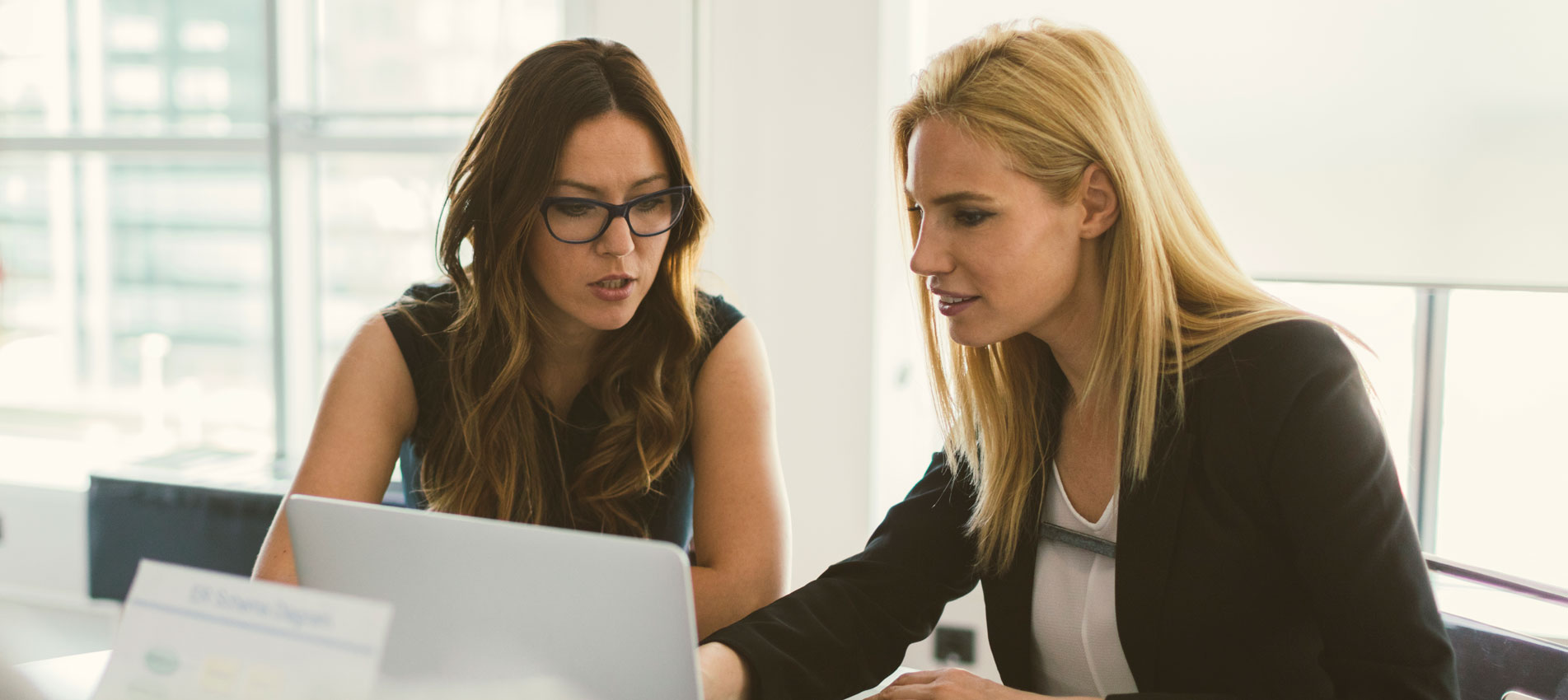 Businesswomen Reviewing Market Graphs And Charts On A Laptop At The Office